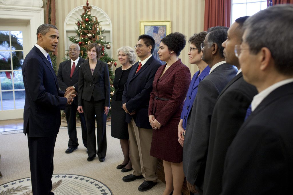 A group of people standing in front of a christmas tree.