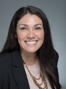 A woman with long black hair wearing a suit.